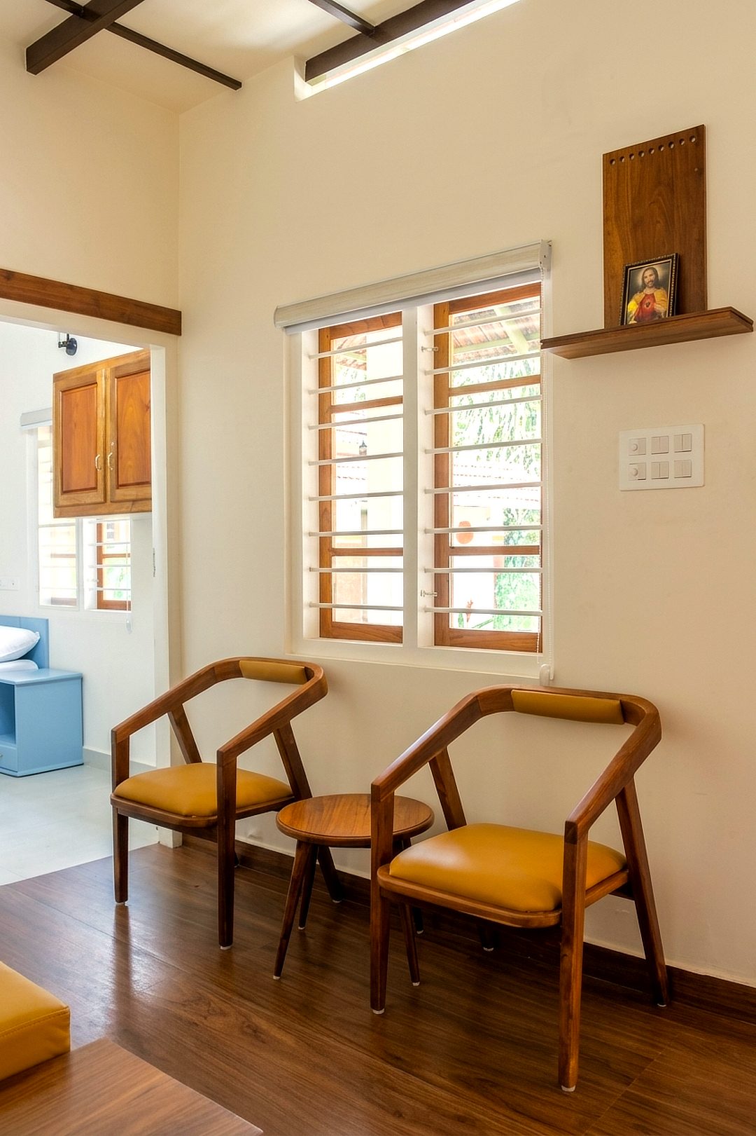 Two wooden armchairs with mustard cushions beside a window
