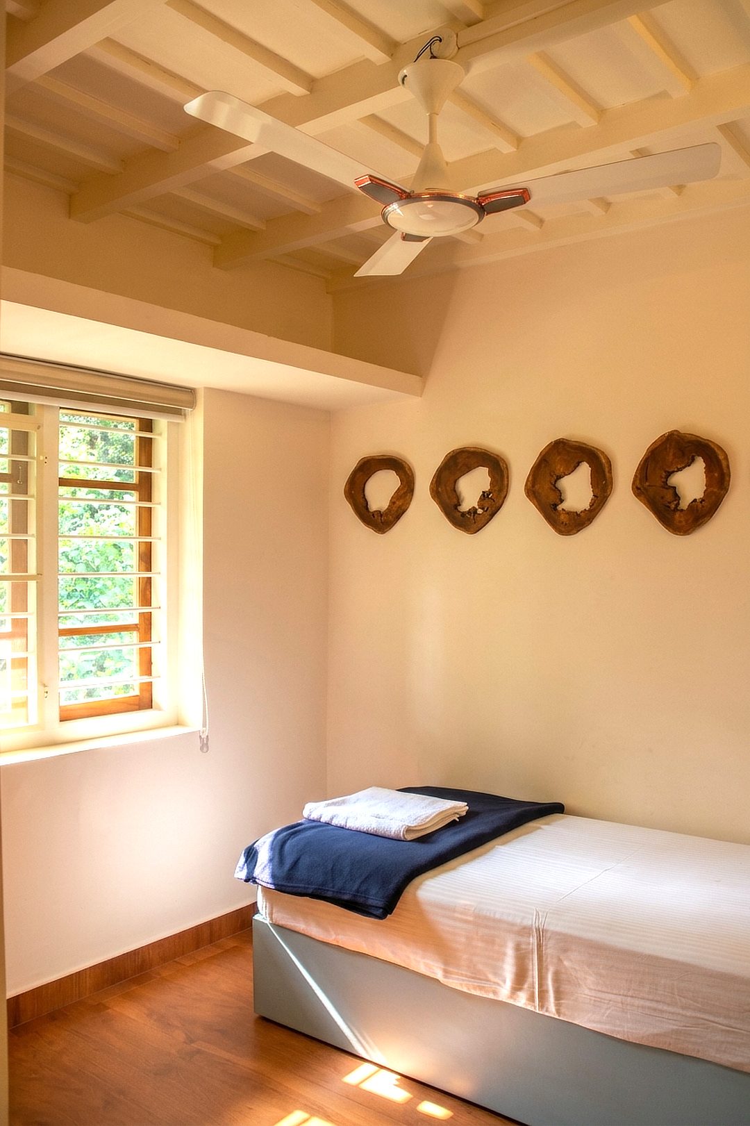 Bedroom with a navy throw, garden window and wooden wall art